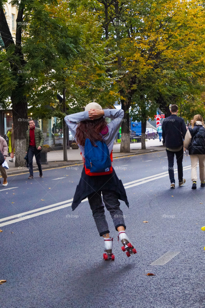 A girl skating along the road in autumn
