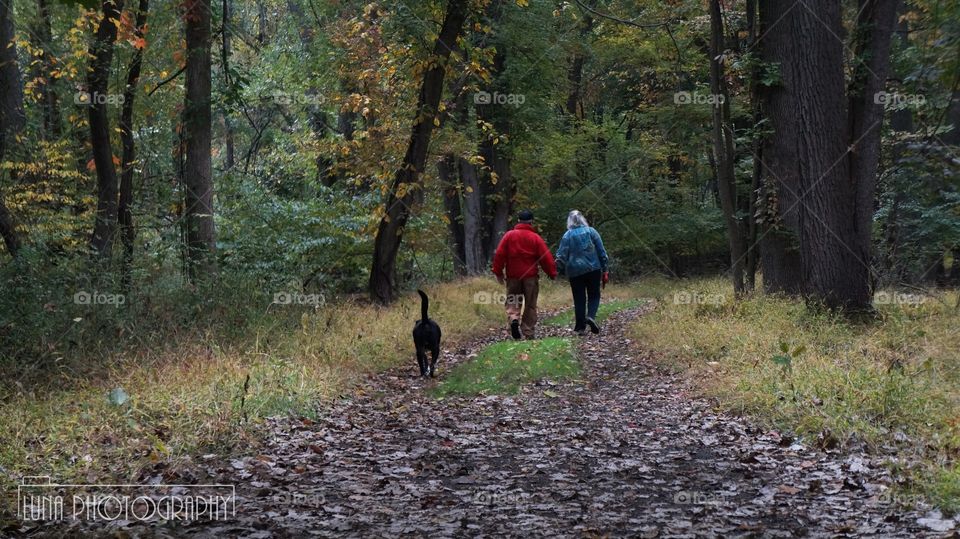 An old couple walks with their dog