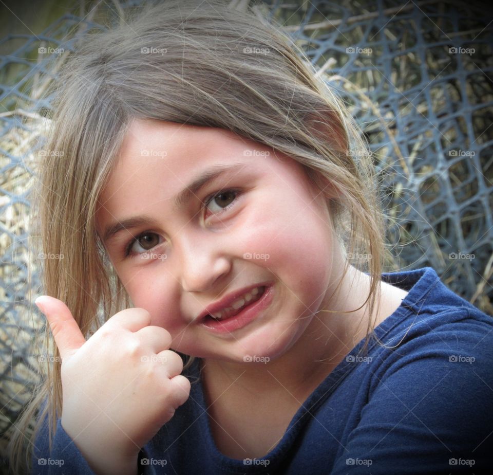 Six year old girl, smiling, missing a tooth and giving a thumbs up!