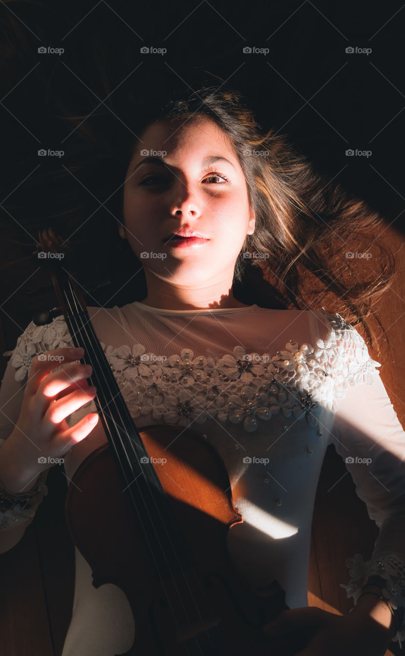 Portrait of young girl lying with a violin in her hand