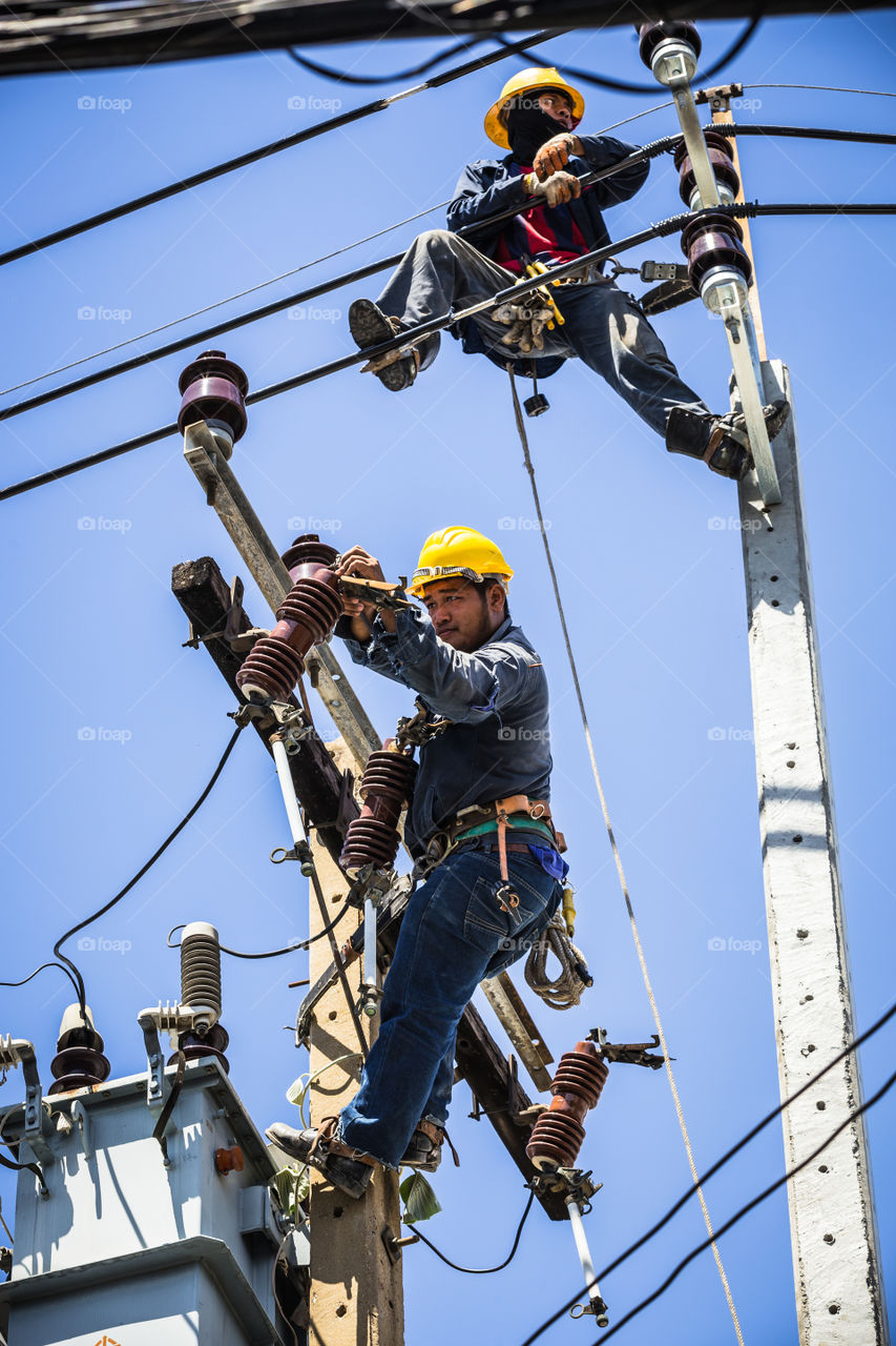 Electrician working together on the electricity pole to replace the electrical insulator