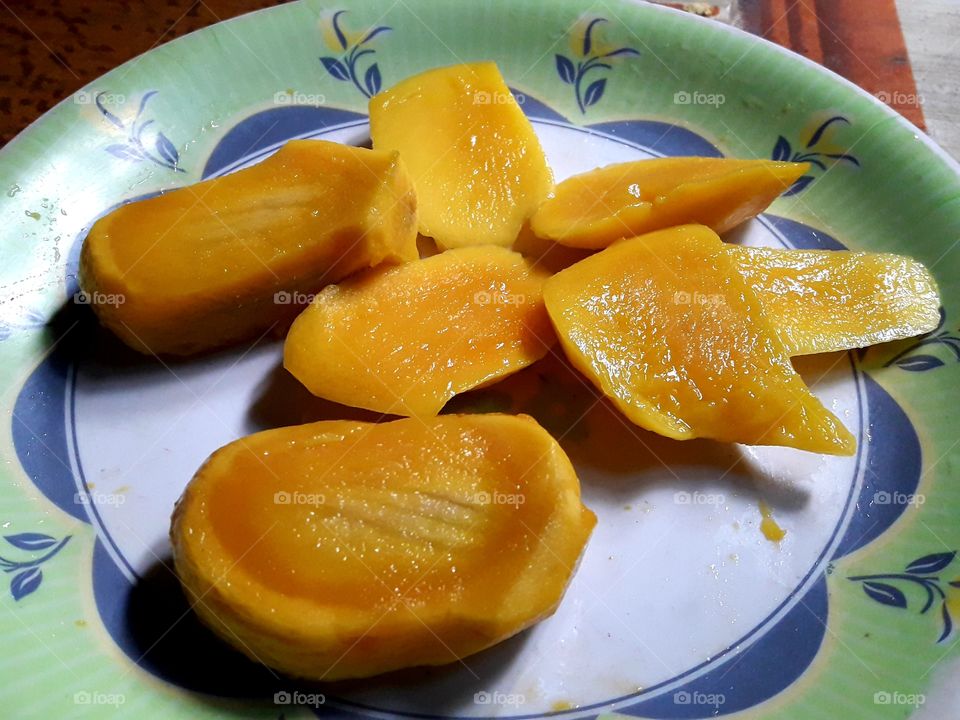 Juicy mango pices on a plat.