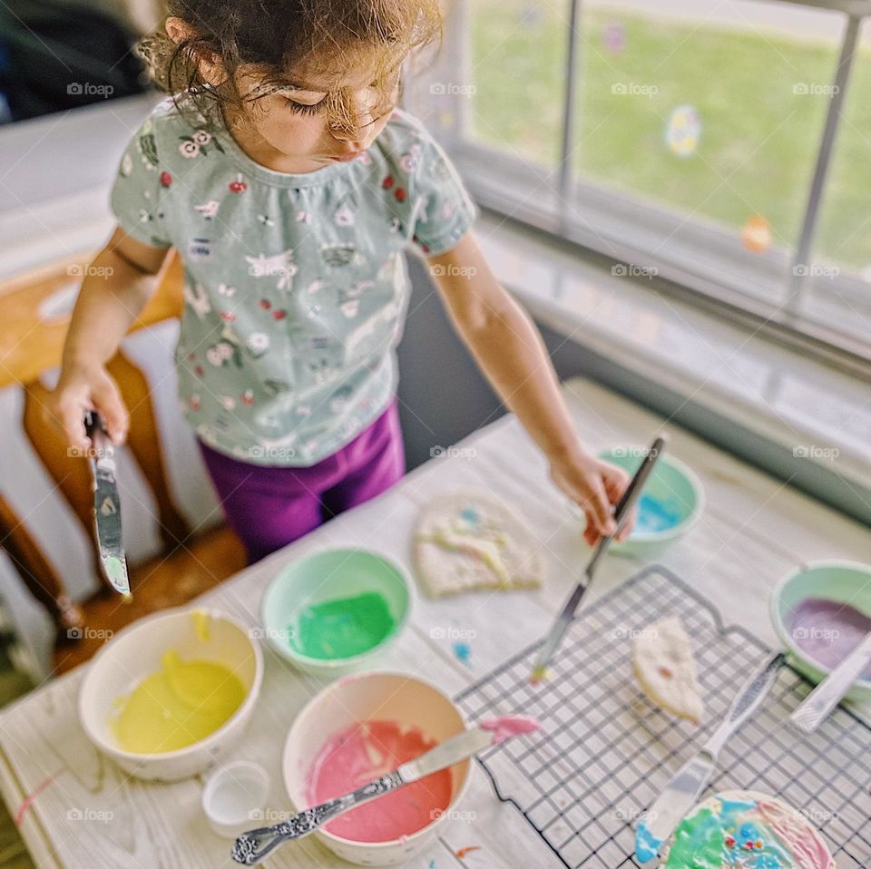 Toddler decorating spring cookies, toddler icing cookies with springtime colors, making homemade sugar cookies, baking with Mommy, in the kitchen with toddlers 