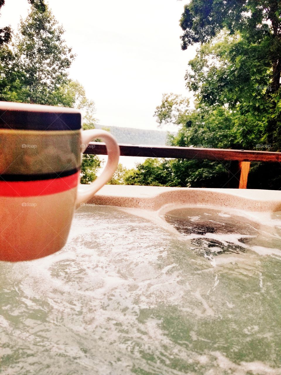Colorful cup of joe to start the perfect morning morning with the peacefulness of the tranquil lake and bubbles of relaxation in the hot tub surrounded by lush greenery of nature.