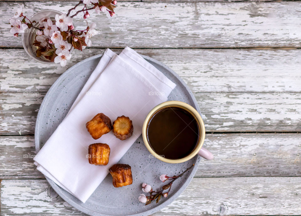 Top view of still life with coffee, cannele and some spring flowered twigs.