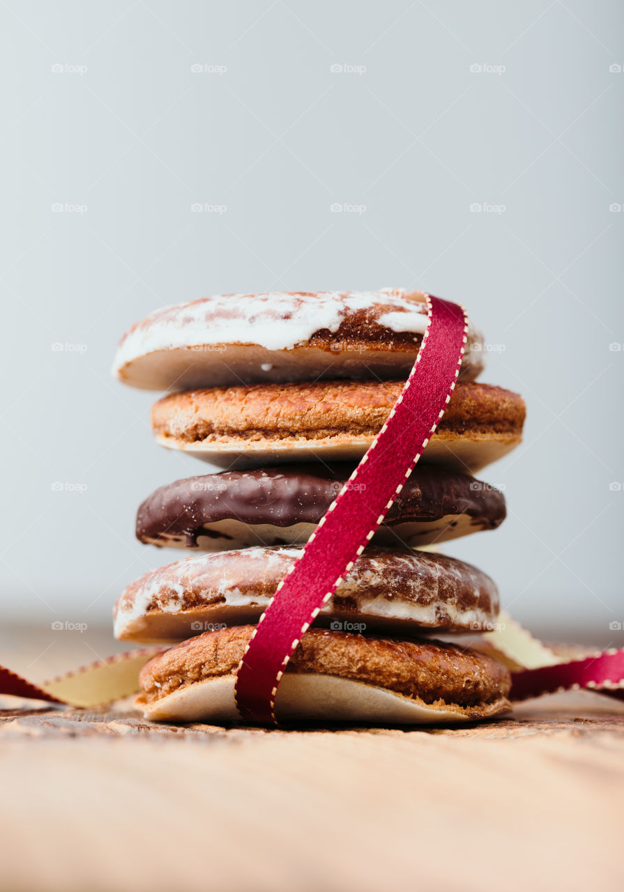 A few gingerbread cookies wrapped in red ribbon Happy Christmas on wooden table. Plain background. Portrait orientation