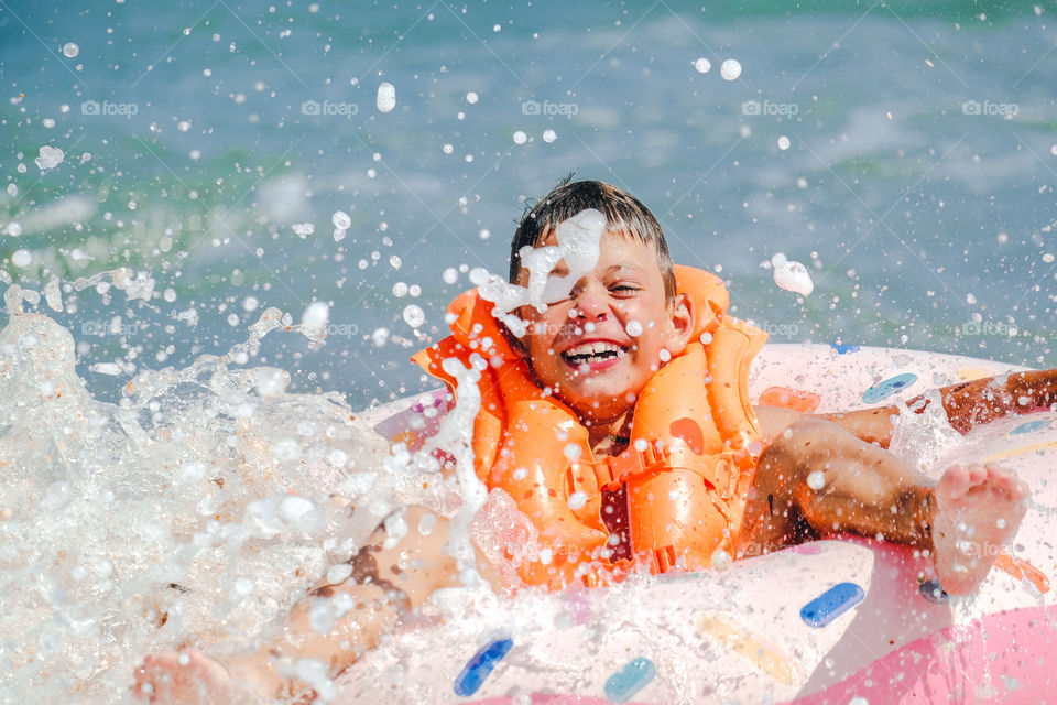 Laughing happy boy in the splashes of water