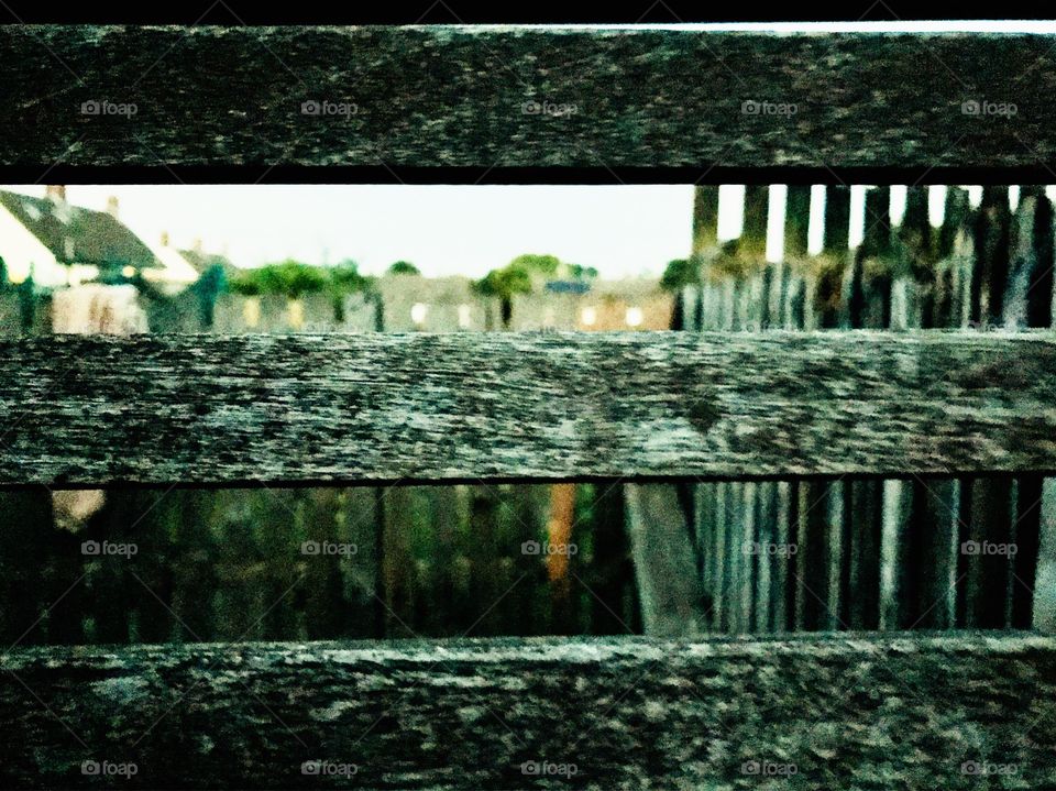 View through the old wooden bench. Houses in background.