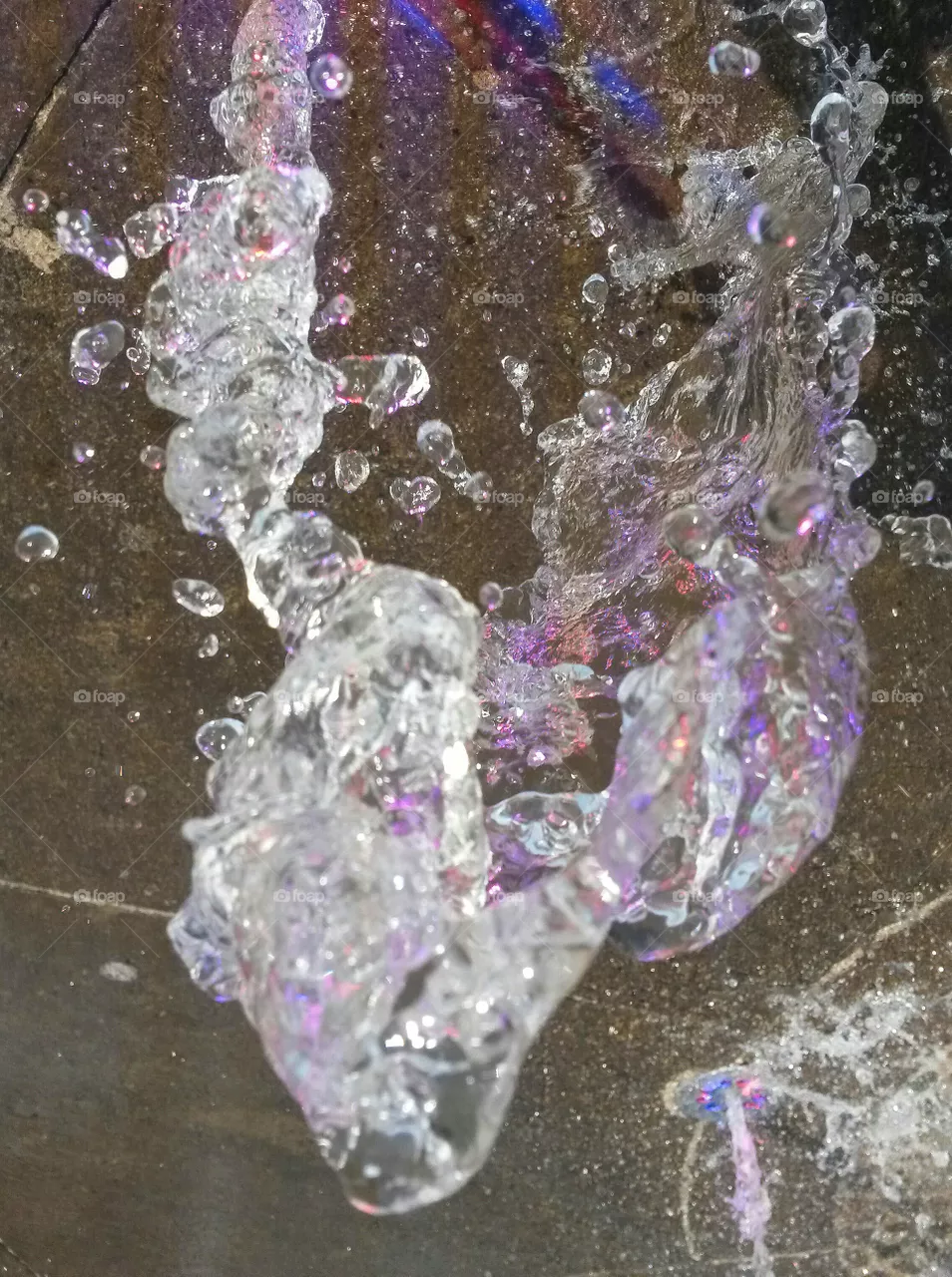 water in motion: Close up of water splash from a fountain with colored light