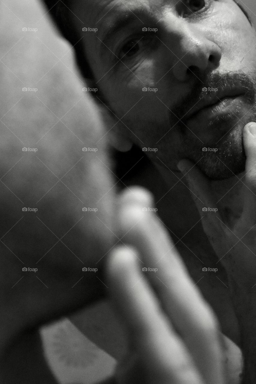 A man looking at his mustache in a mirror 