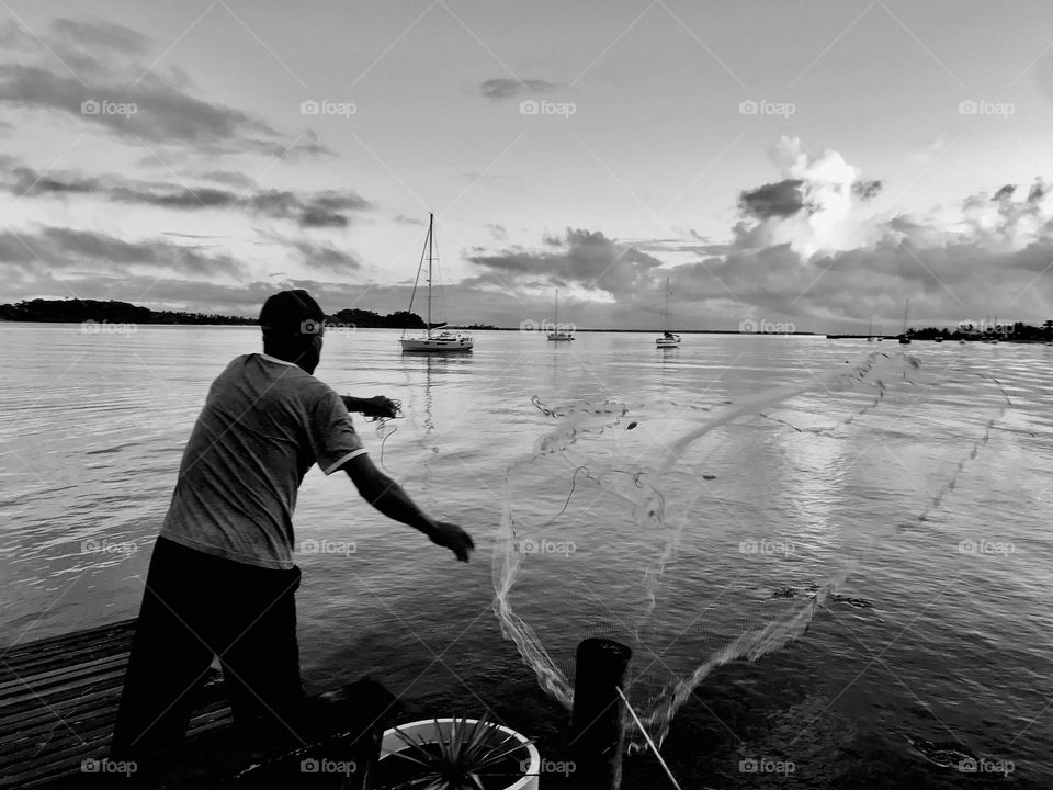 fisherman throwing fishing net in the sea at dawn of day