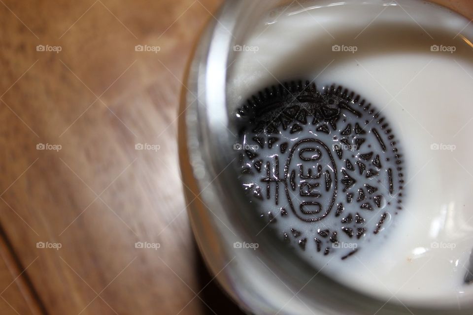 And Oreo sitting in milk on a table in a mason jar or glass