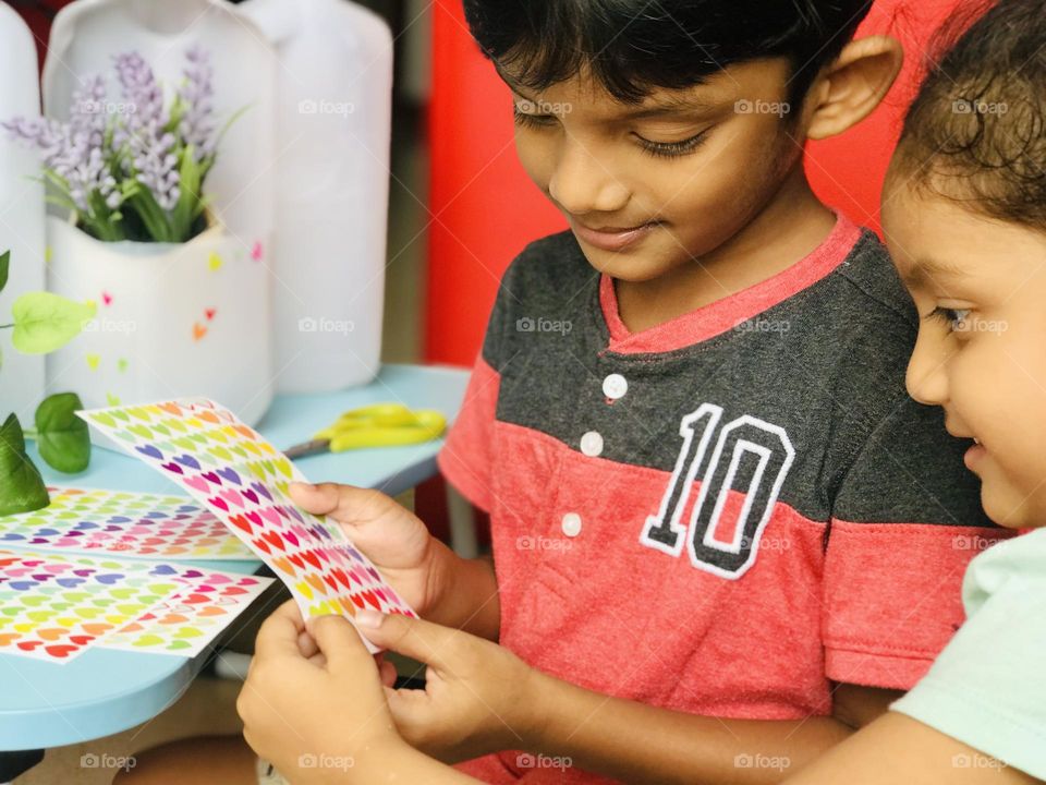 Kid’s doing craft with smiling faces and they turned leftover plastic bottles into a flower pots.