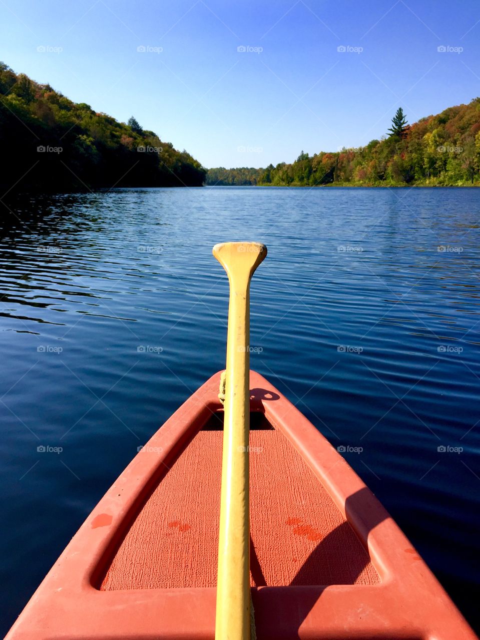 A red canoe on a lake with autumn colours.