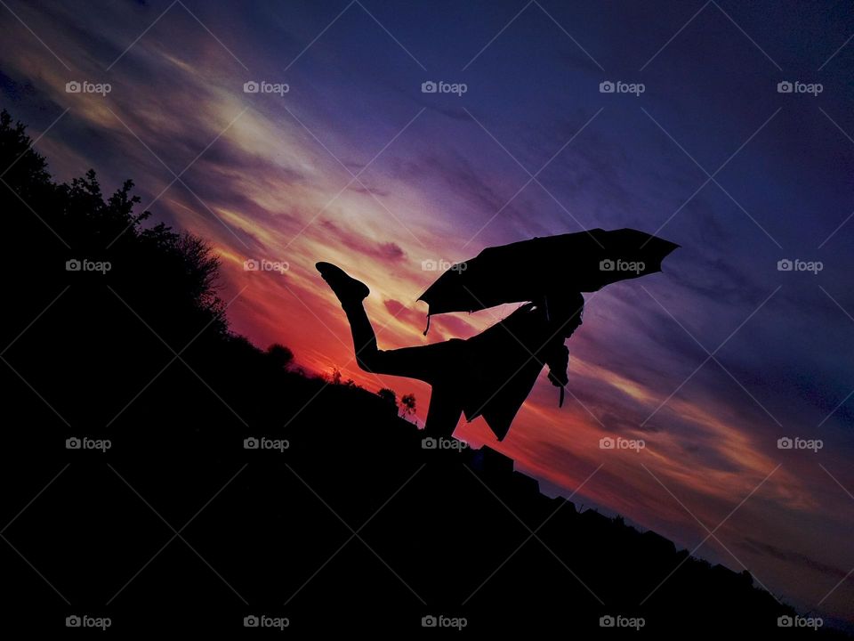 Girl with umbrella on sunset background