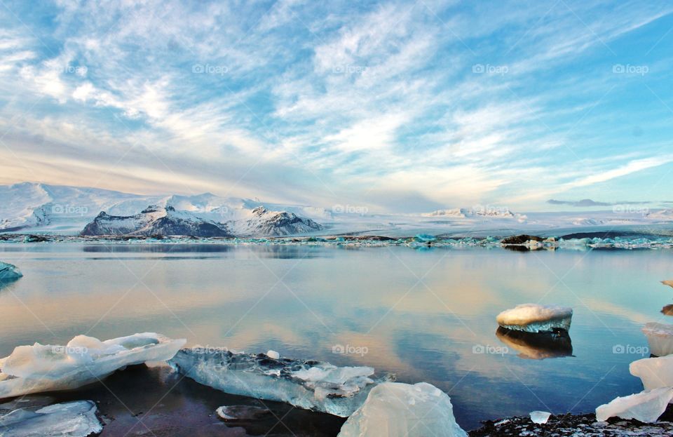 glacier lagoon of Iceland. ice blocks like giant crystal floating on a lake mirror. with snow hills as backdrop