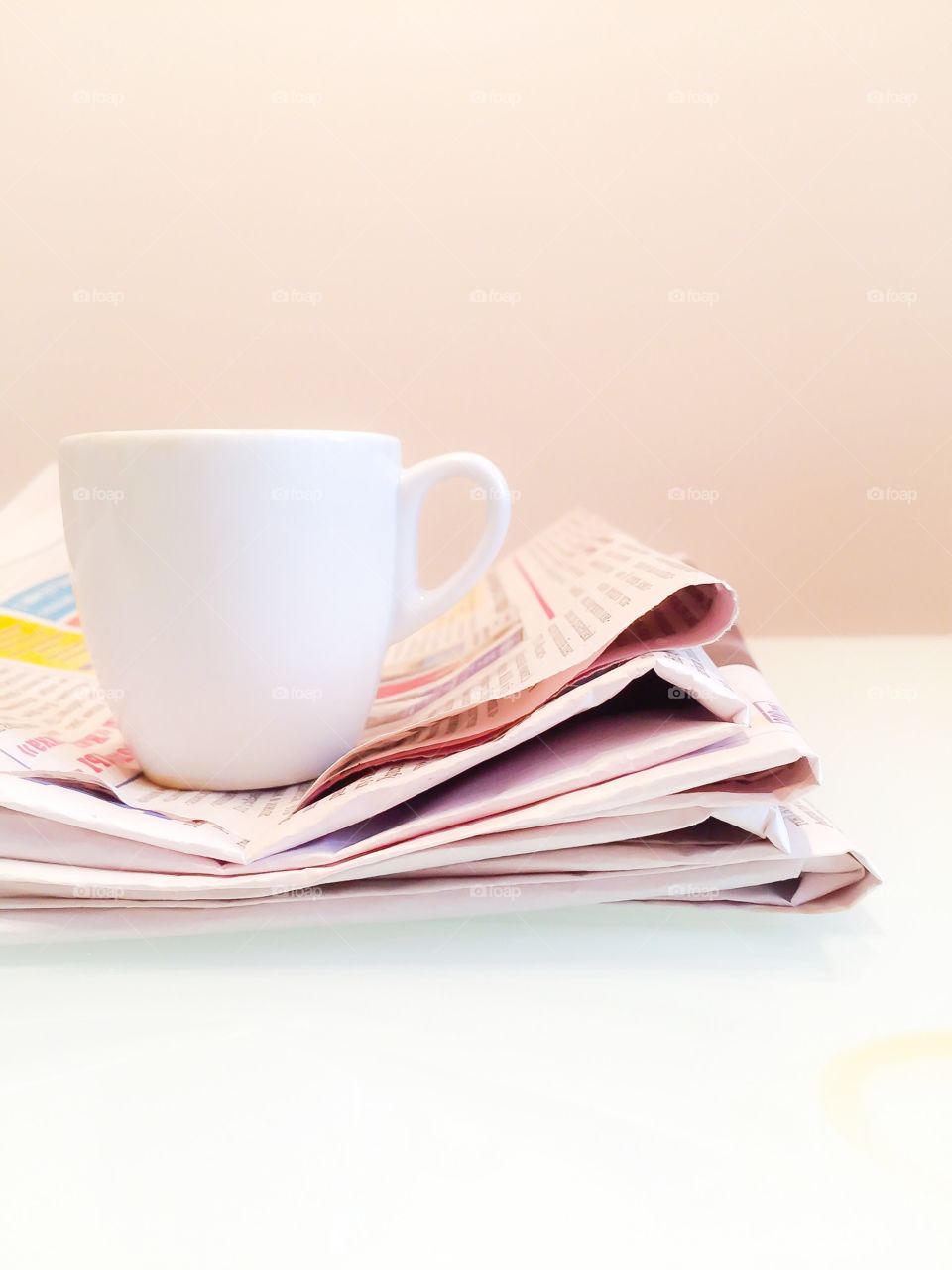 Read newspapers are stacked. And cup of coffee on the top