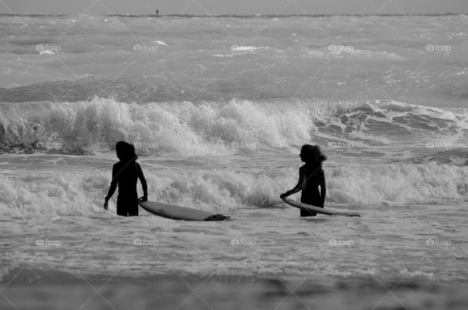 Two girls with surfboat in sea