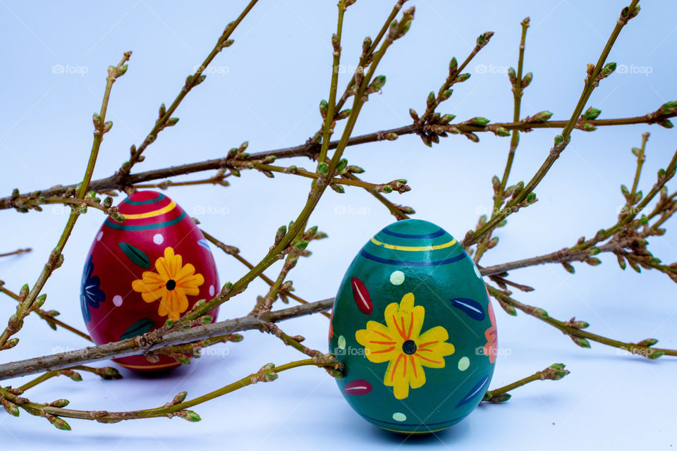 Two colored wooden Easter eggs within blooming spring branches