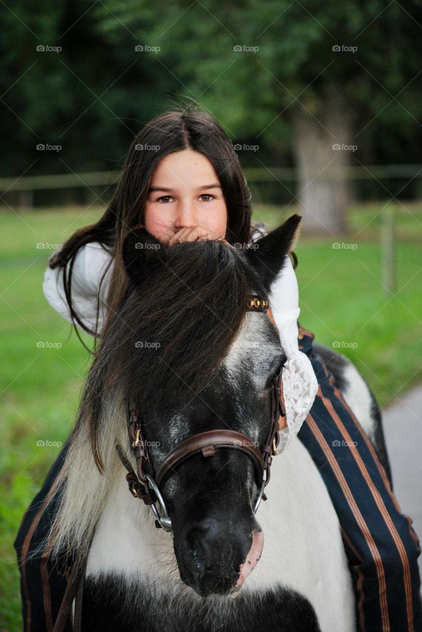Girl with long brown hair hugging a horse with black manes