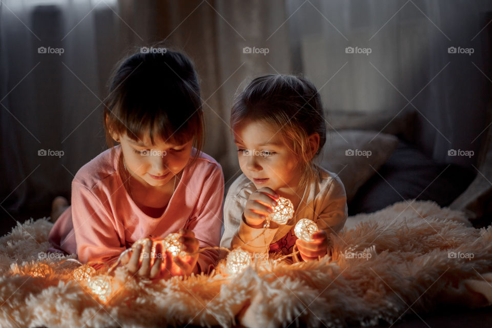 Little sisters reading a book at Christmas time 