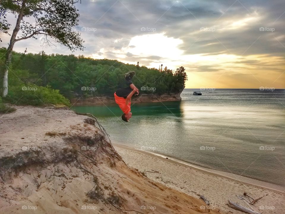 Back flips off Sandune by beach at sunset