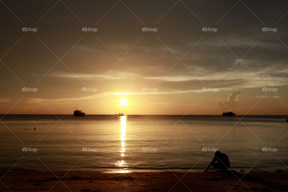 Golden hour in Koh Tao, Thailand. A beautiful colourful sunset, you can feel the peace and the local customs. Small boats.