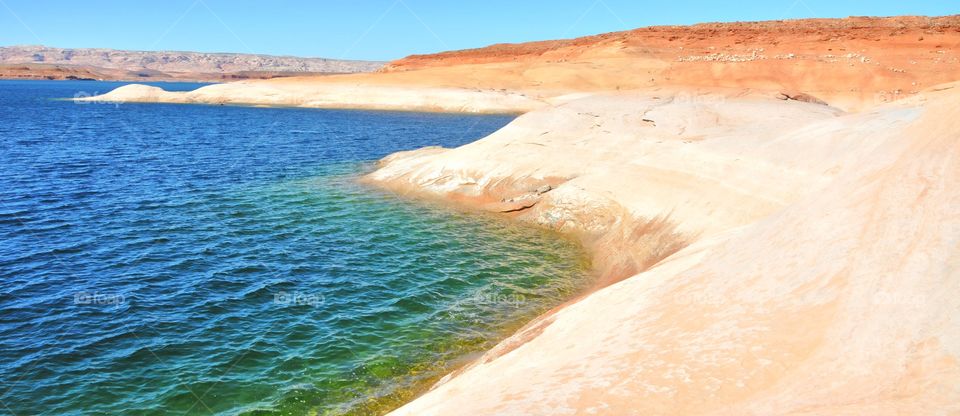 Lake Powell on a sunny summer day. The water is colorful and very inviting. The land is bare and rugged.