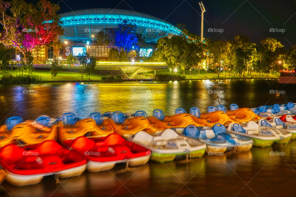 Adelaide Oval Football stadium at night with paddle boats in the foreground 