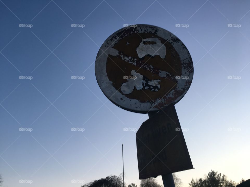 Worn and dilapidated street sign in the sunset