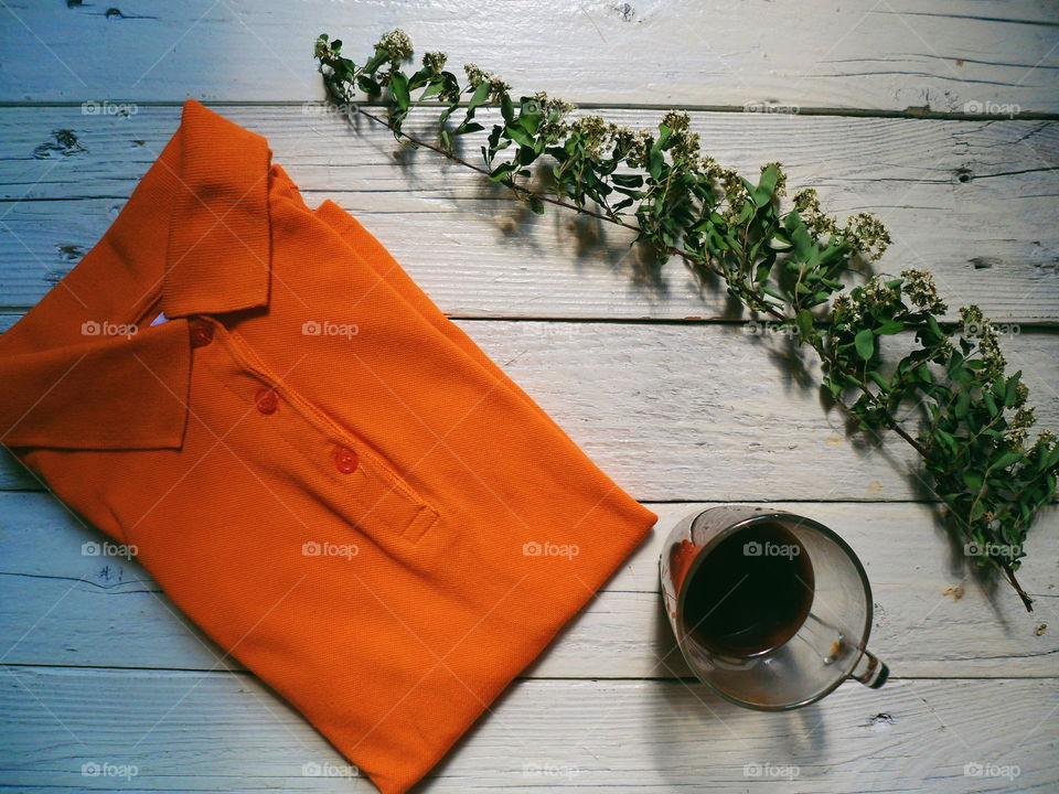 Orange fashionable shirt, dry twig of flowers and a cup of black coffee