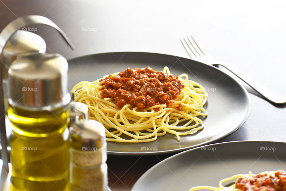Spaghetti Bolognese with minced beef, onion, chopped tomato, garlic, olive oil, stock cube, tomato puree and Italian herb. Traditional Italian food in black plate. Selective focus.