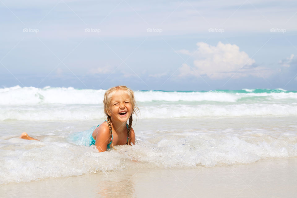 Happy little girl with blonde hair swimming in sea