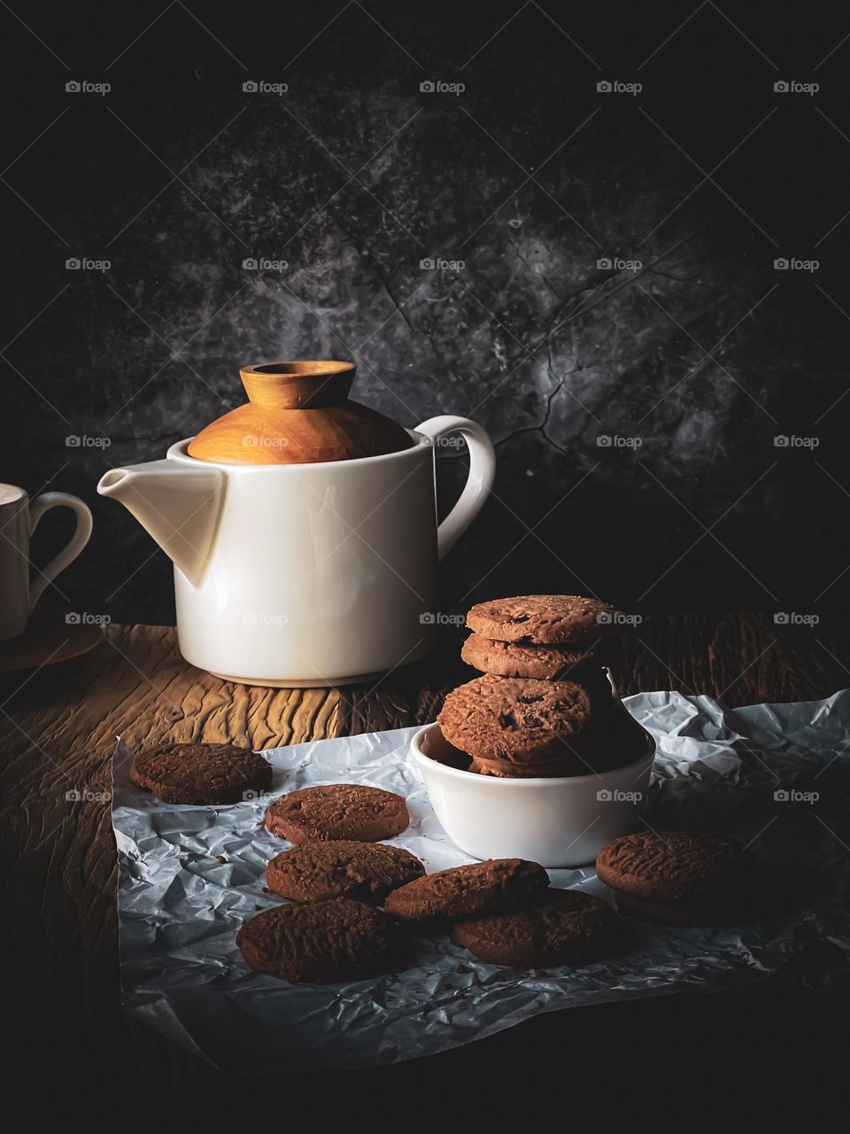 Delicious cookies stacked in a bowl with drinks in dimmed light. 