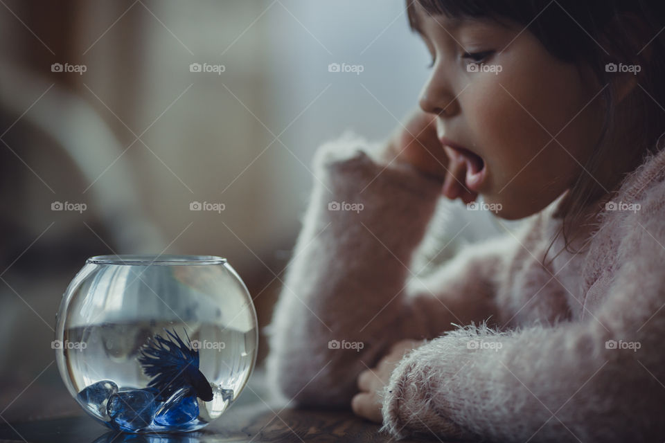 Girl with fish in round aquarium.