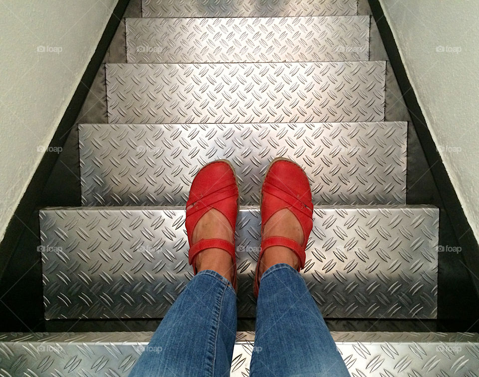 Standing with red shoes on top of the iron stairs