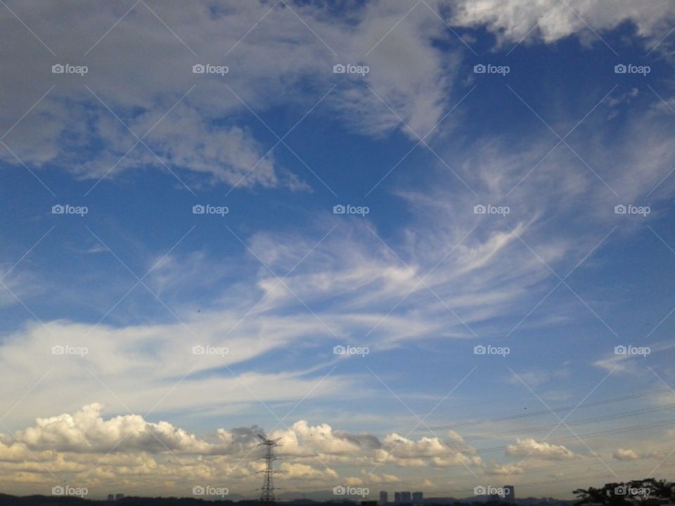 A sunny day with three different clouds in the blue sky.