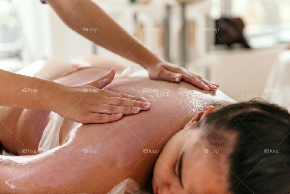 Masseuse doing back massage with skin peeling on young woman