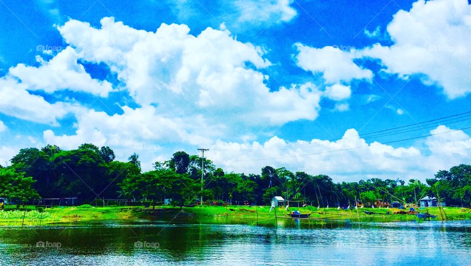 Beautiful blue sky with white clouds and green riverbank 