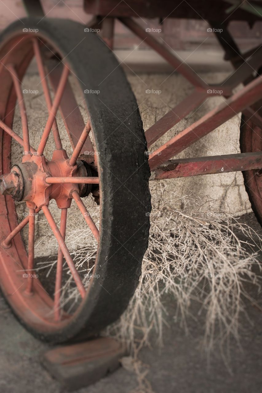 Wagon wheel on baggage cart in front of desert train station.  