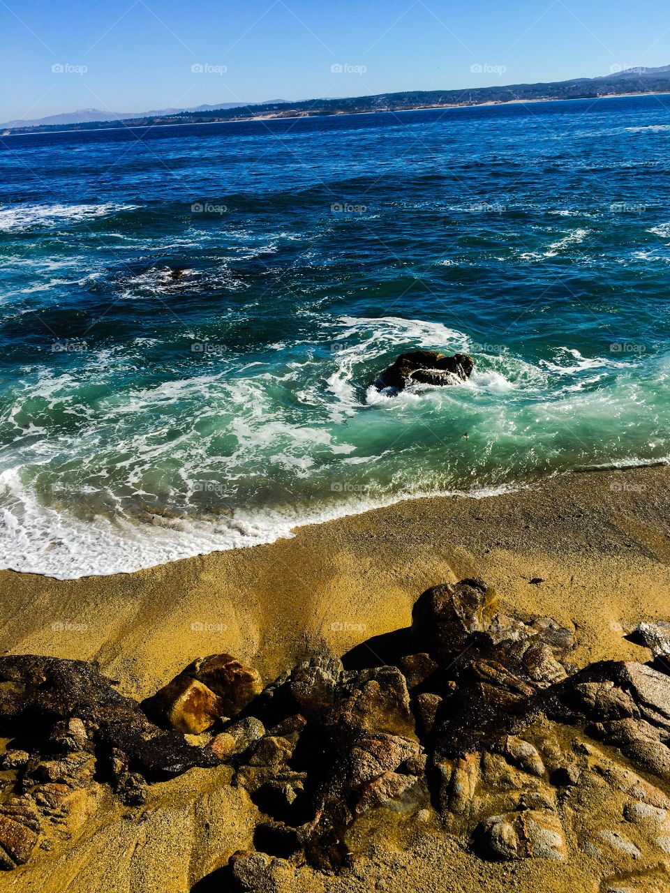 Surf, sand and rocks; surf rolling onto beach in Monterey California 