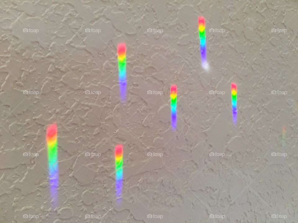 Spectral rainbow light on the wall from the light rays through crystals .