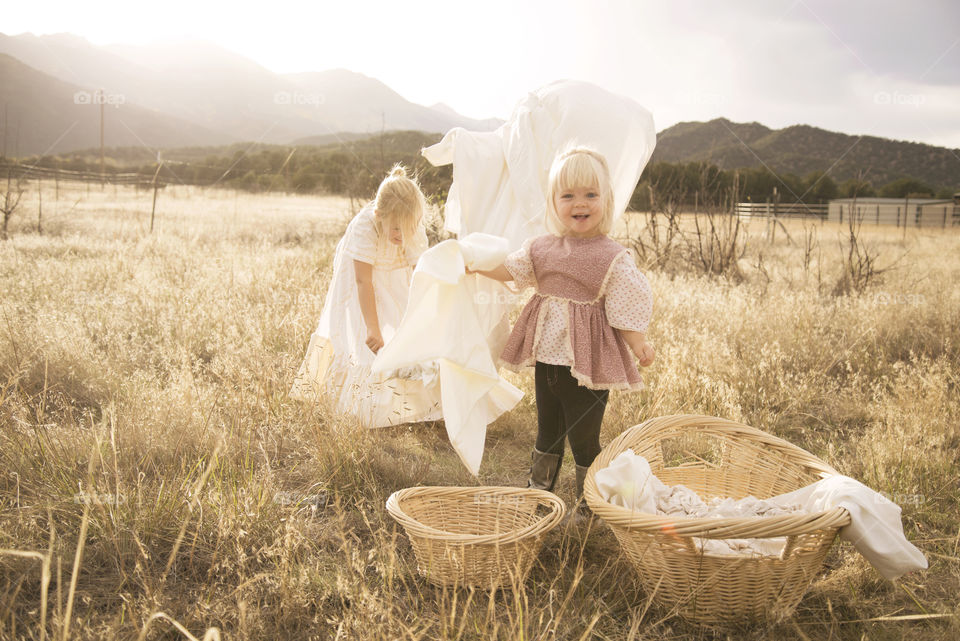 Happy little girls in field with wicker basket