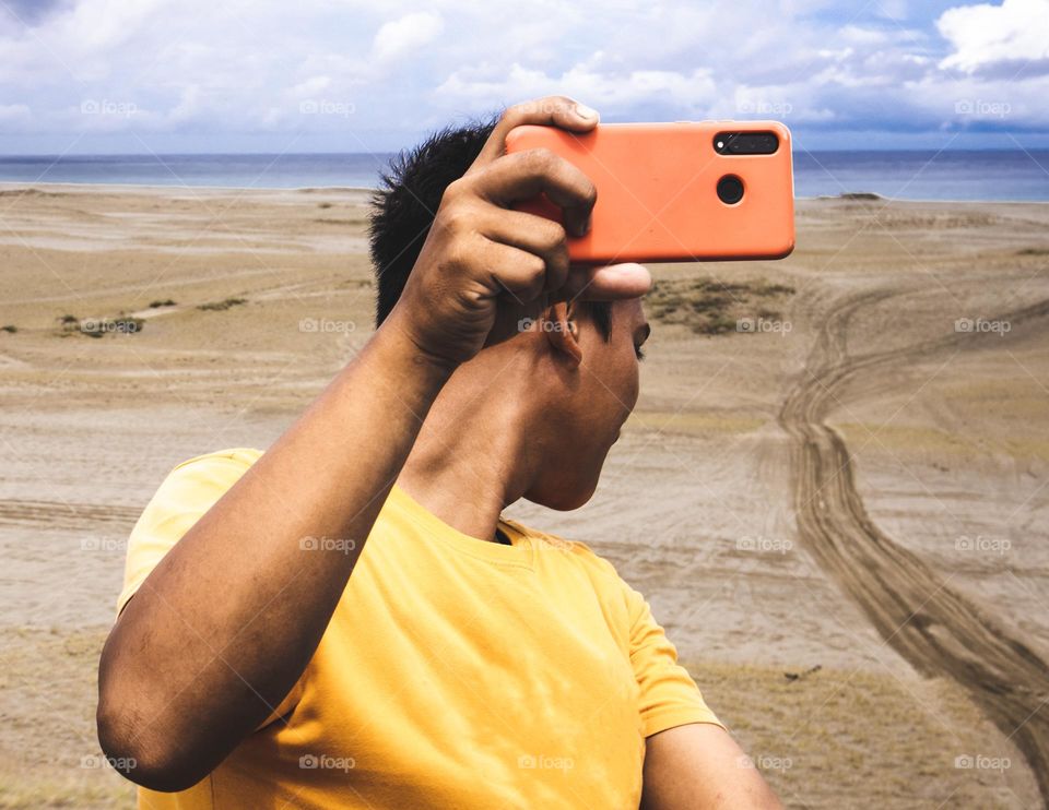 Man holding a cellphone recording an adventure in the sand dunes adventure in Paoay Sand Dunes Philippines