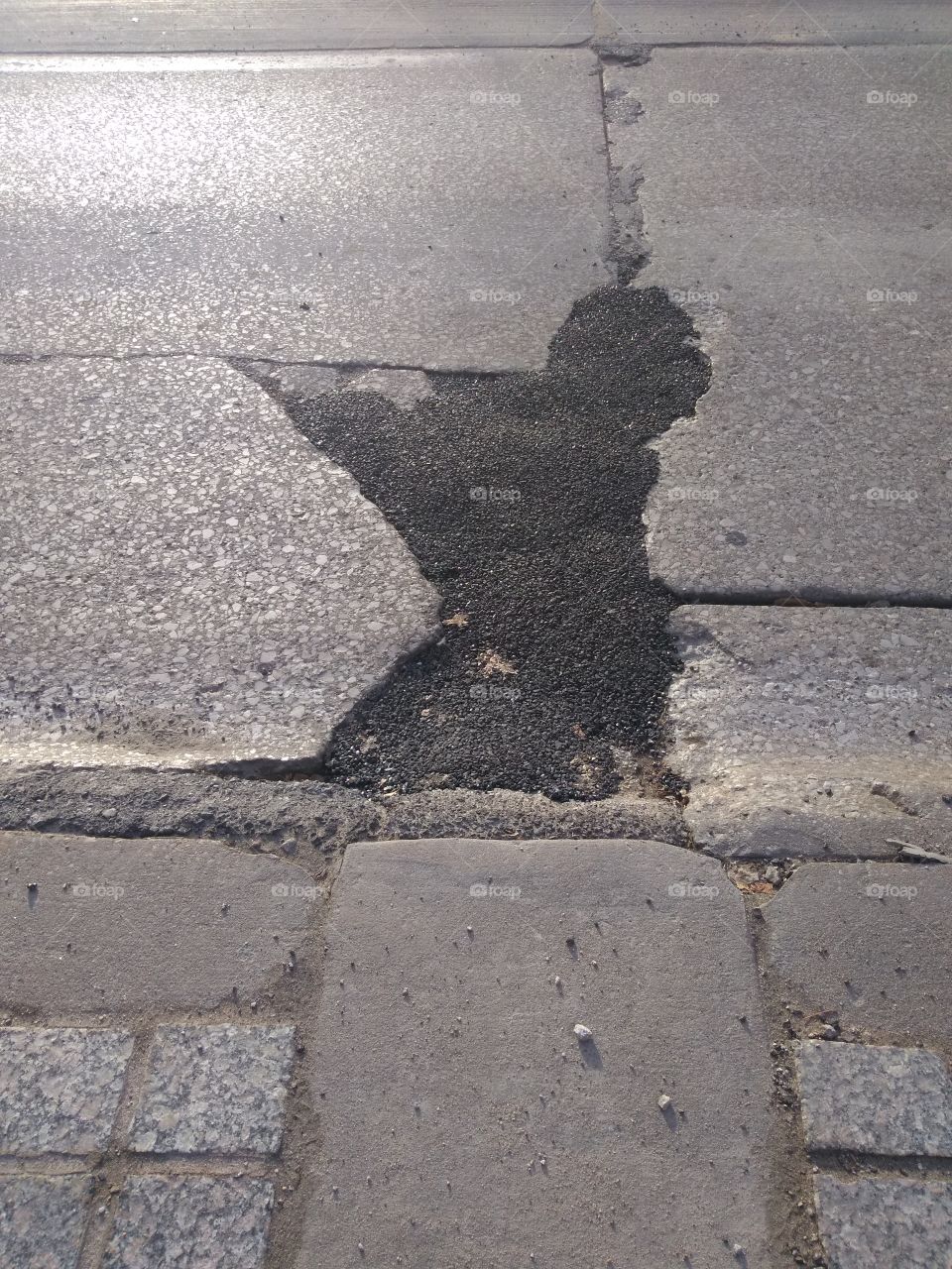 pot hole in street that has been patched/filled in.