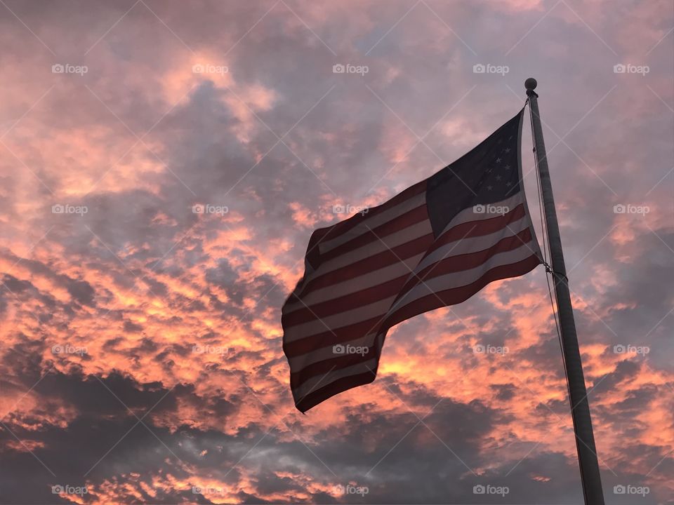 Waving American flag in front of sunset glowing clouds