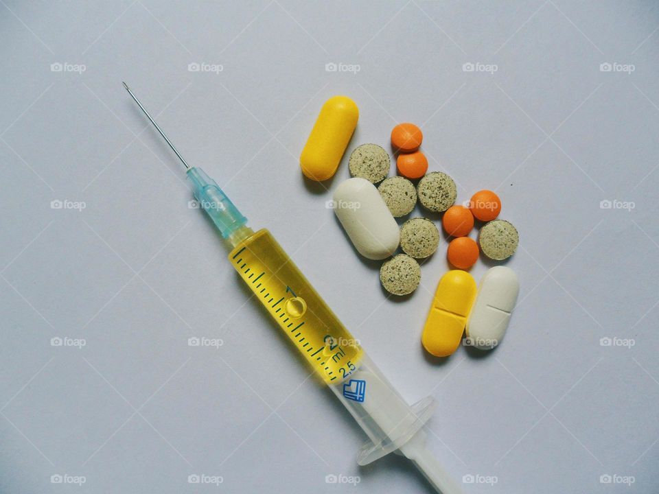 medical syringe, tablets and pills are on a white background