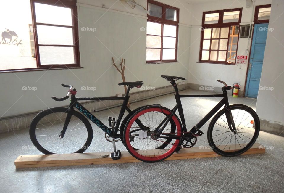 Two bicycles are indoors. black bike