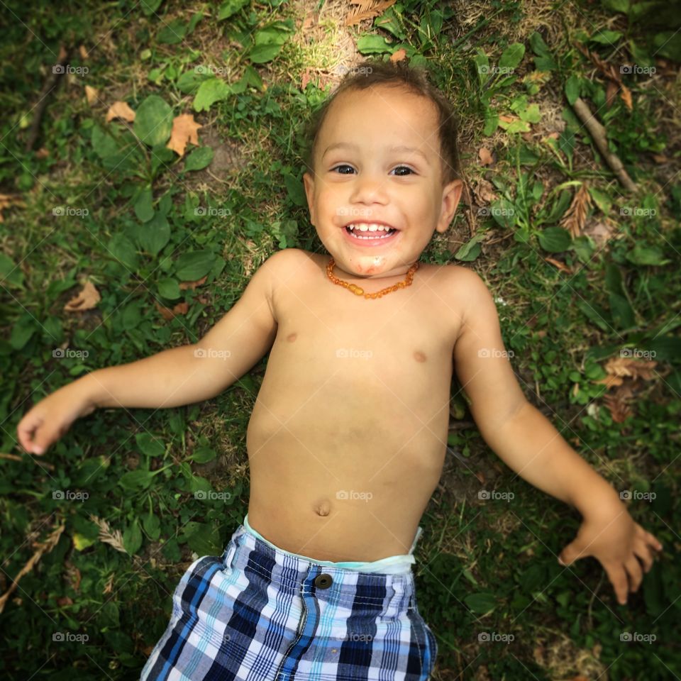 Baby boy laying on grass in shade