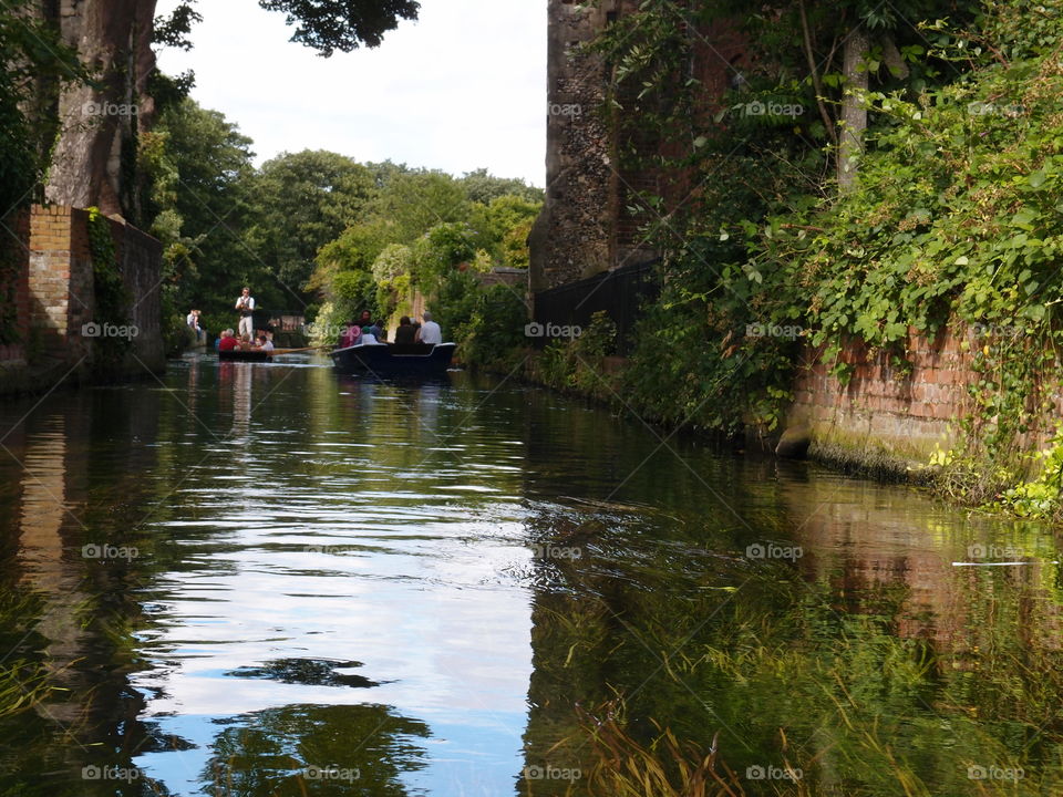 During a boat tour the York River in England flows by brick buildings on a summer day 